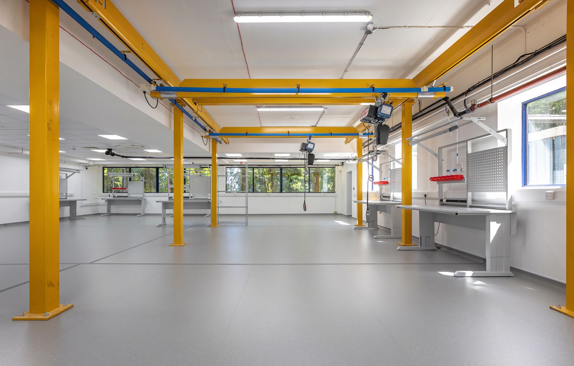 A large empty room with a yellow crane on the ceiling.