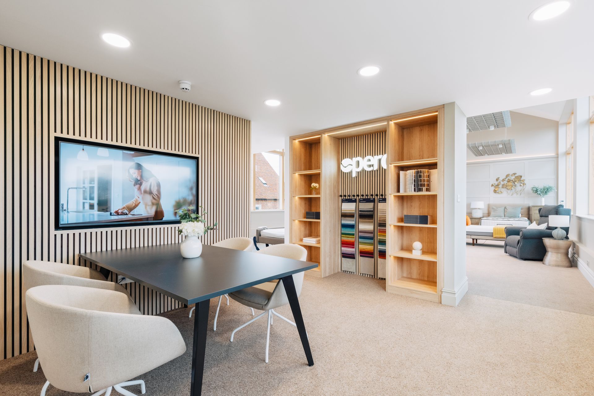 A showroom interior with a table, chairs, a TV, and shelves displaying samples.