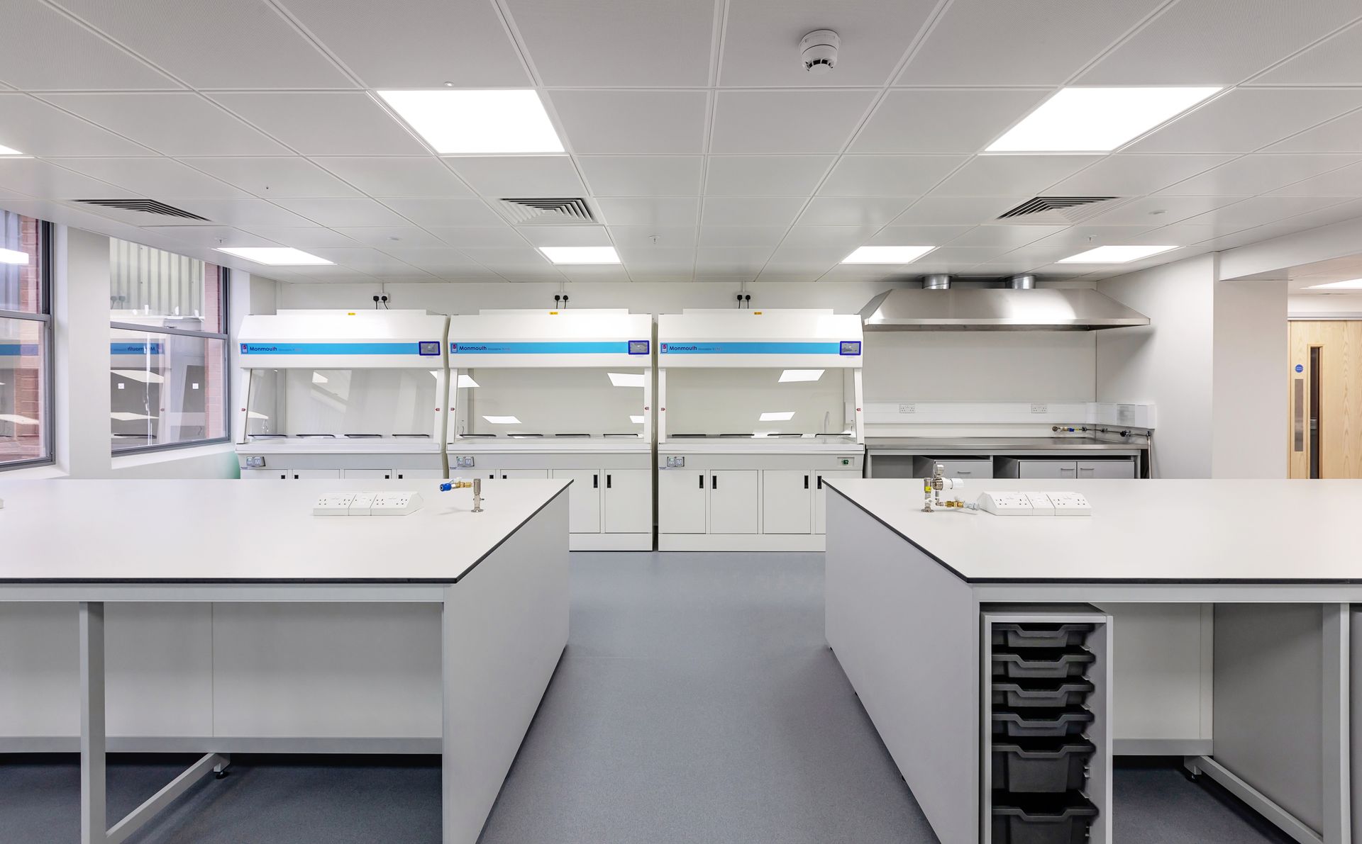 A woman in a lab coat is walking down a hallway in a laboratory.