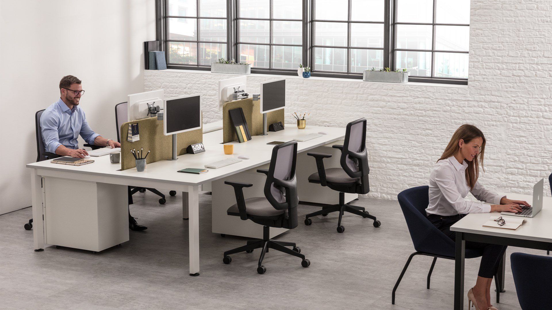 A man and a woman are sitting at desks in an office.