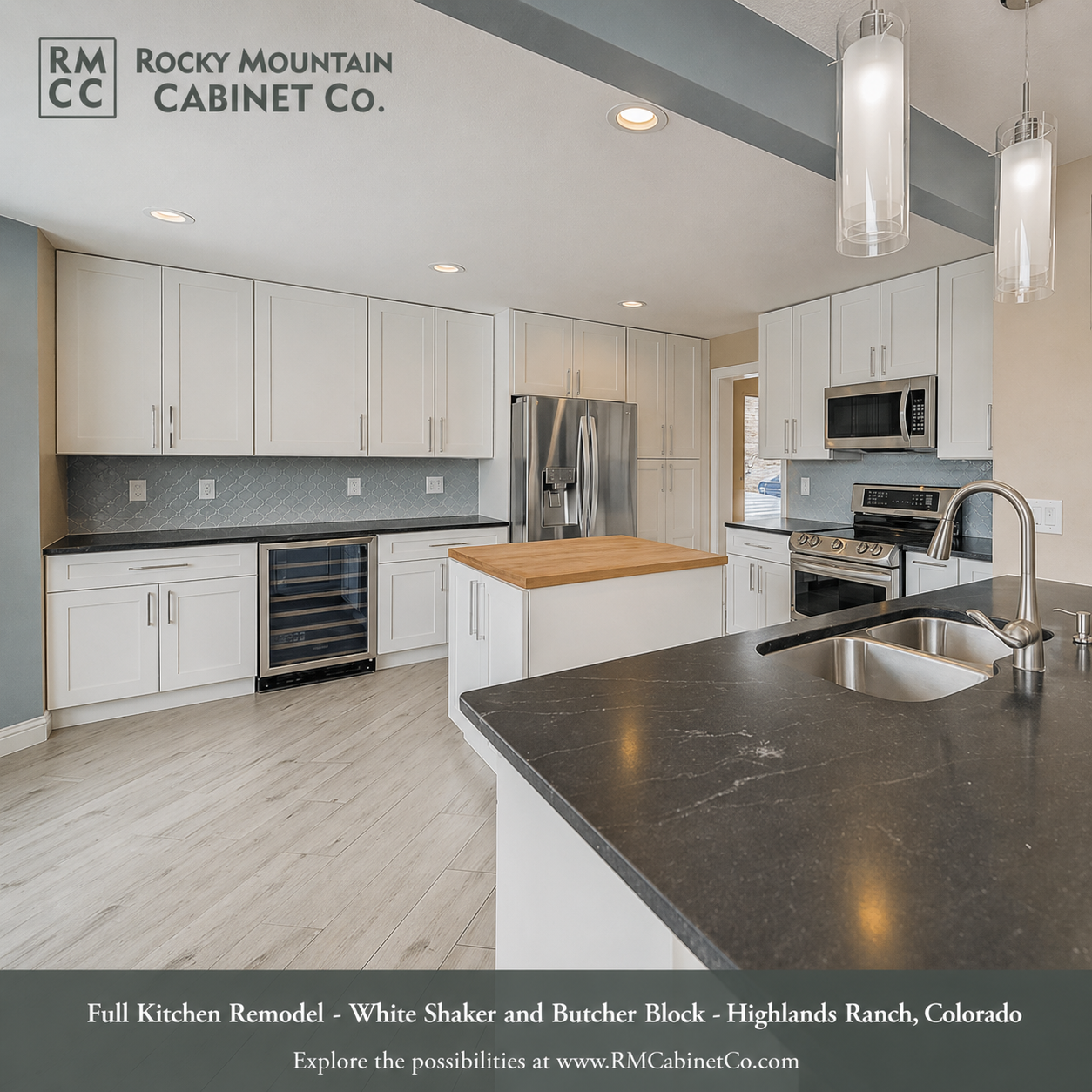 A modern kitchen with white cabinets, dark countertops, a central island, and three pendant lights hanging over the sink.