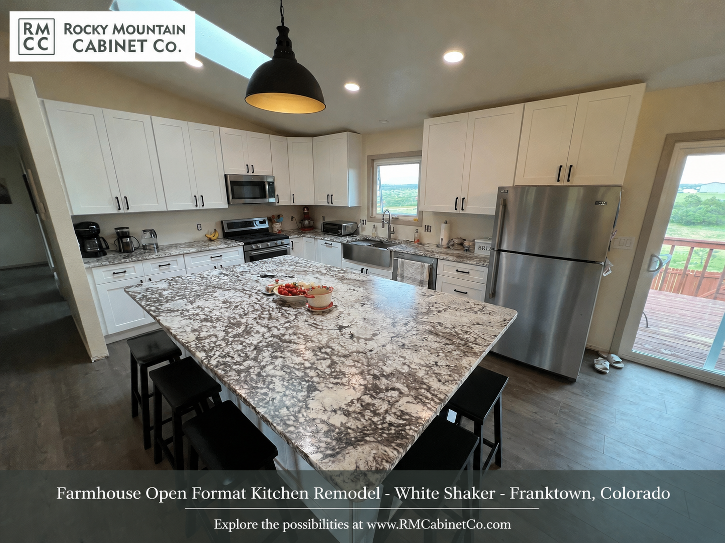 Modern kitchen with white cabinets, granite island with four black stools, stainless steel appliances, and a skylight.