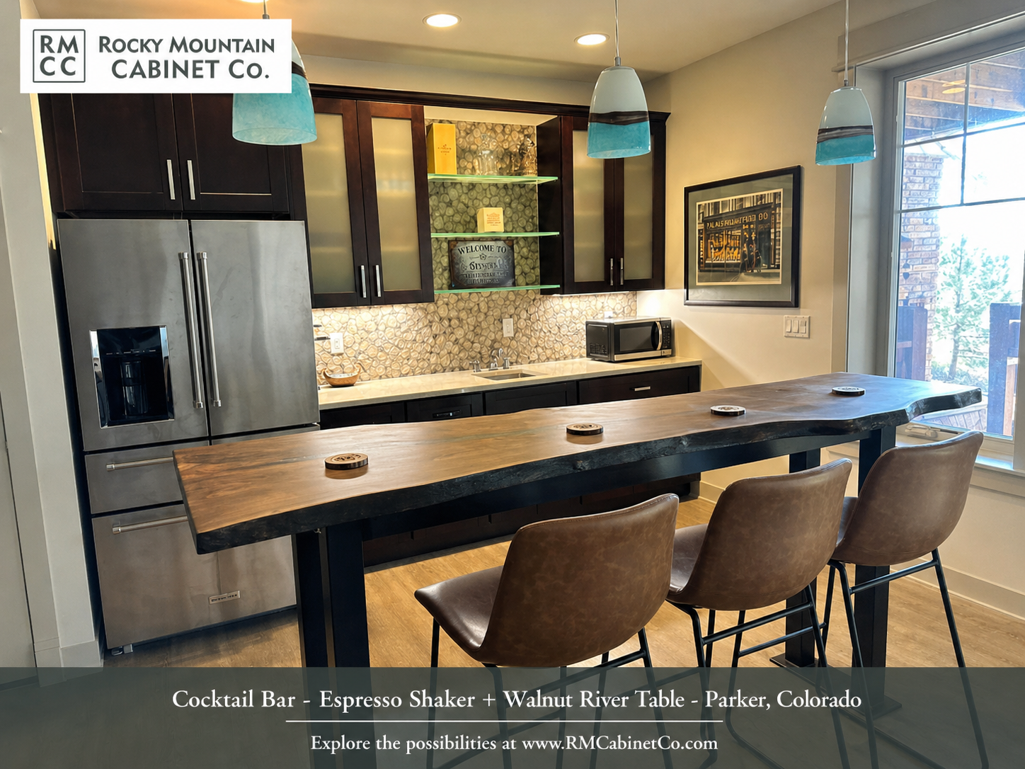 Modern kitchen with dark cabinets, stainless steel refrigerator, patterned backsplash, and wooden bar with three stools.