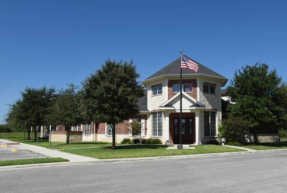 Two-story brick building with an American flag on a pole in front.