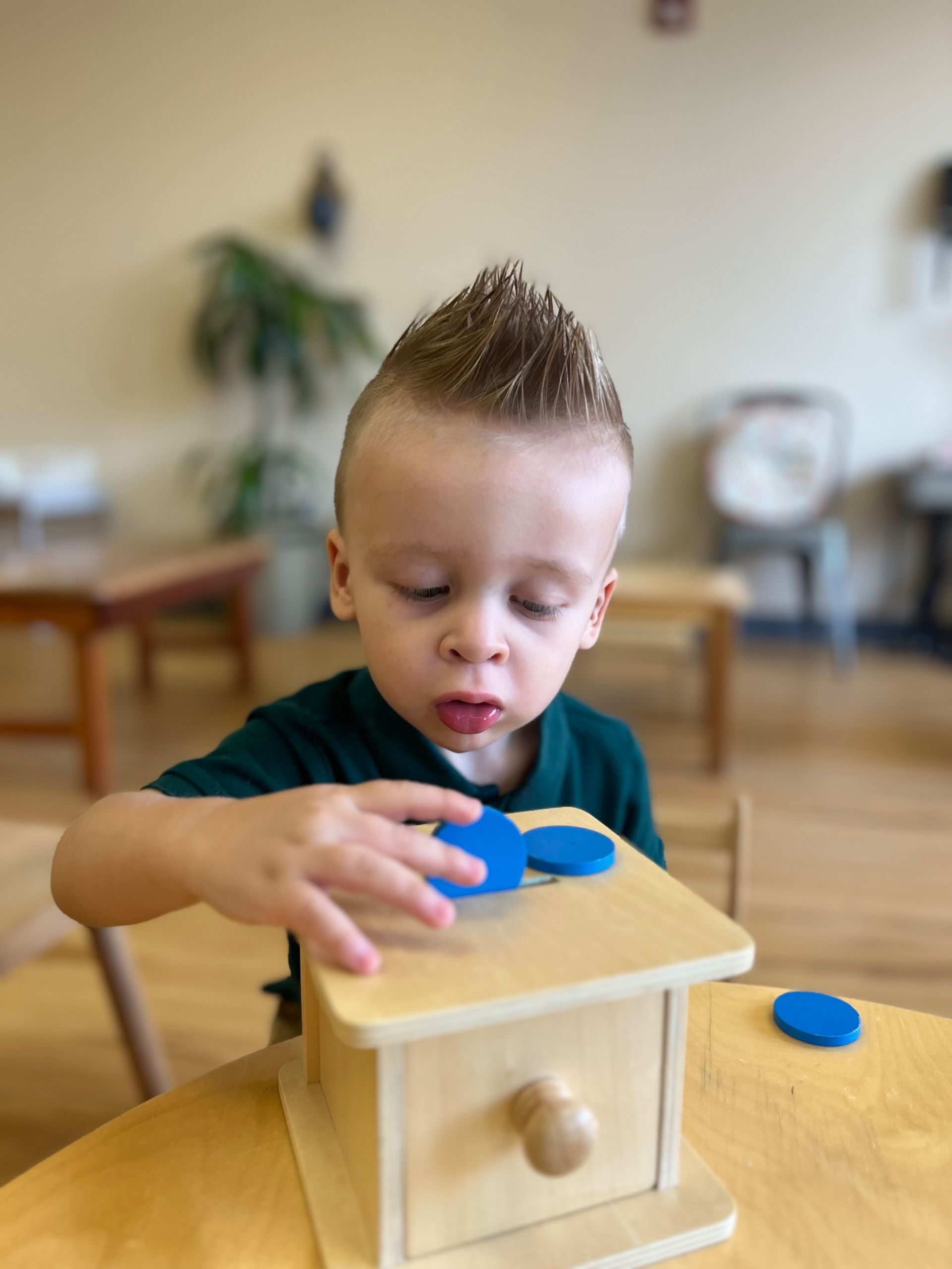 A young boy is playing with a wooden montessori toy.