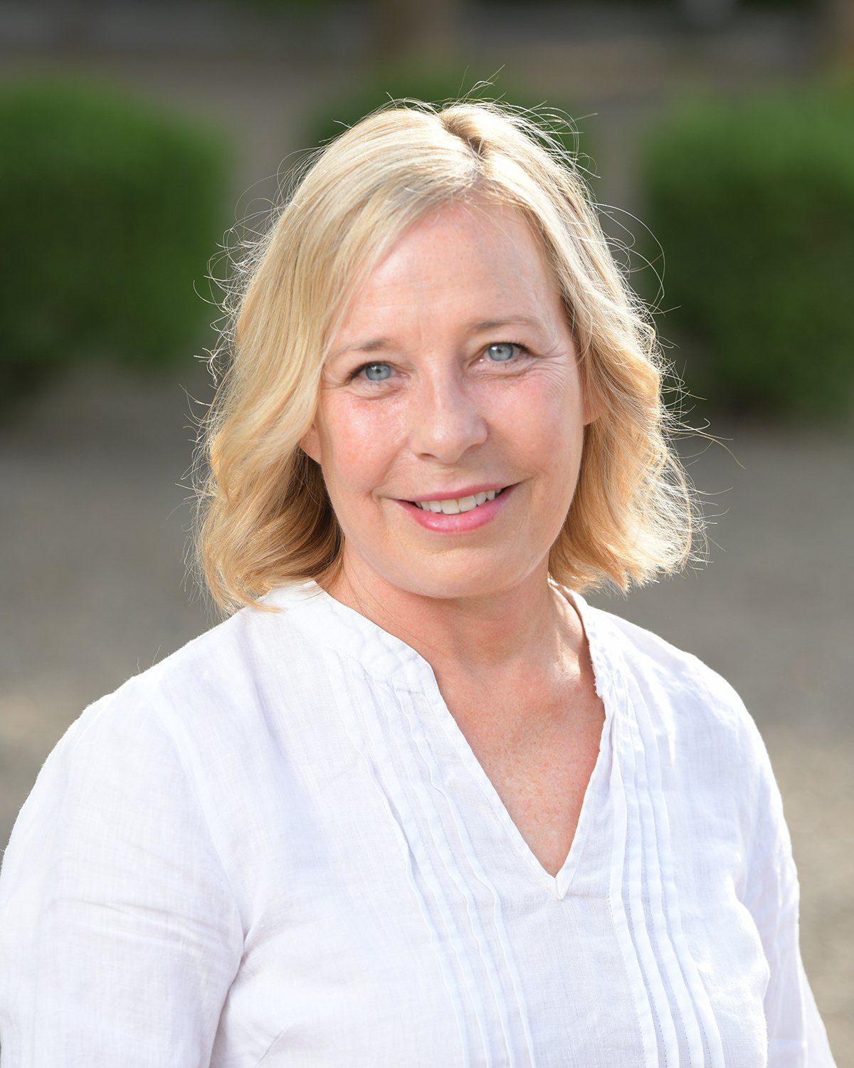 A woman in a white shirt is smiling for the camera.