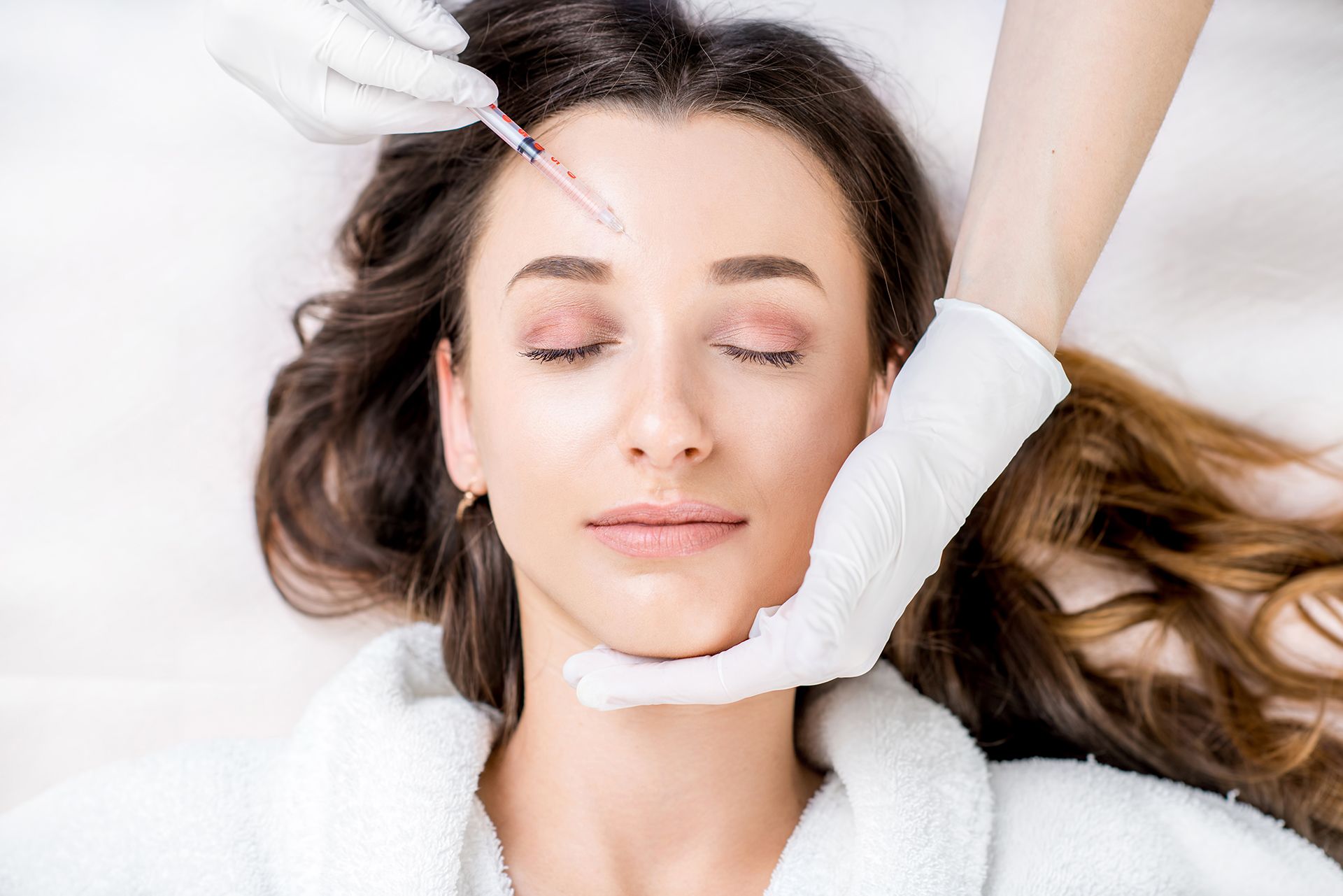 Woman receiving cosmetic injection in forehead