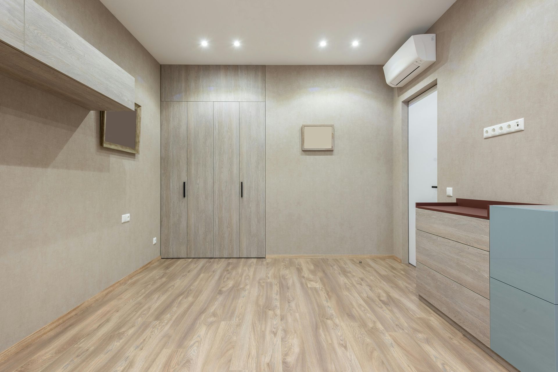 Empty room with light wood floors, closet, chest of drawers, and open door.