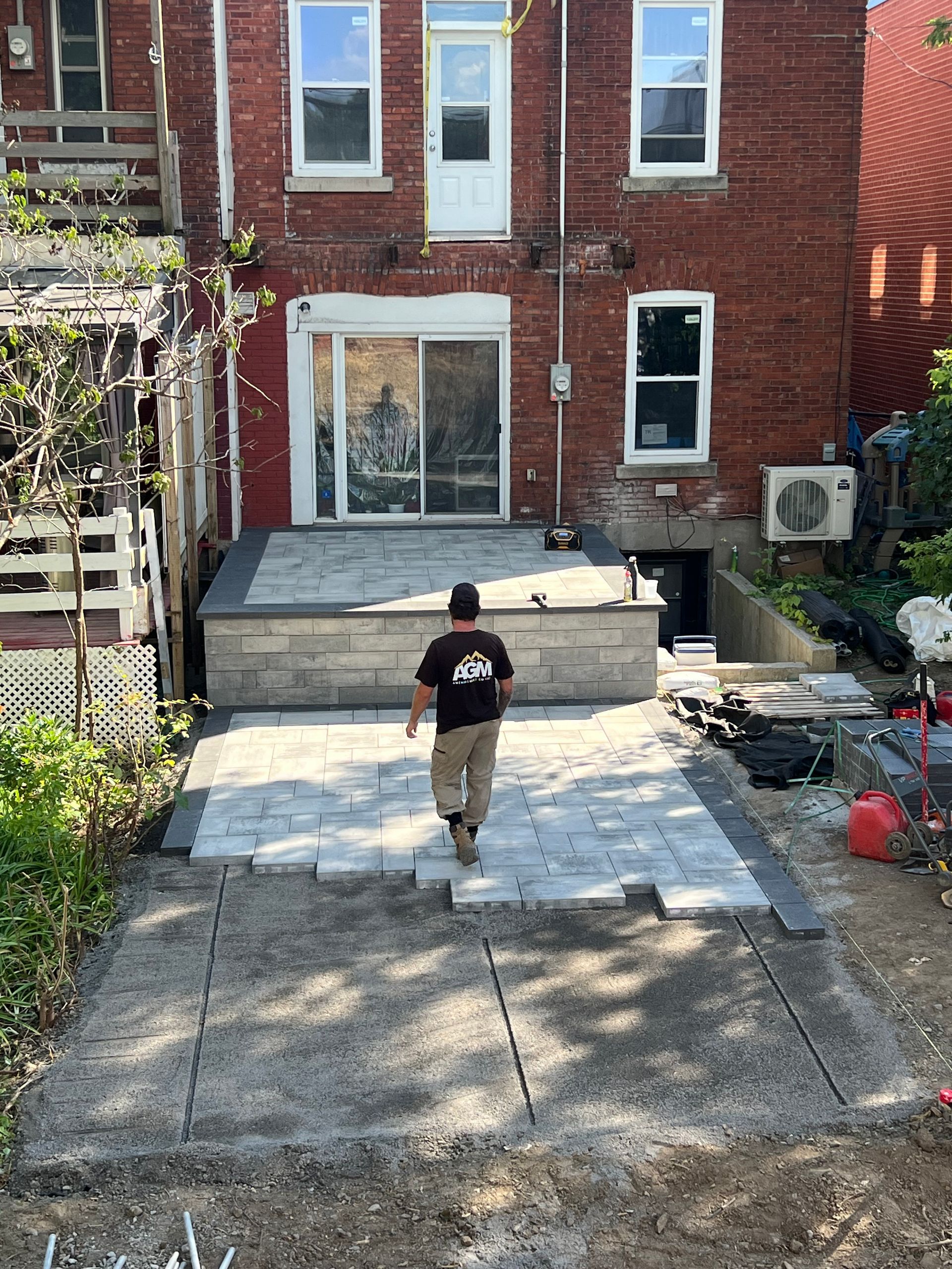 Un homme marche sur une terrasse devant un bâtiment en briques.