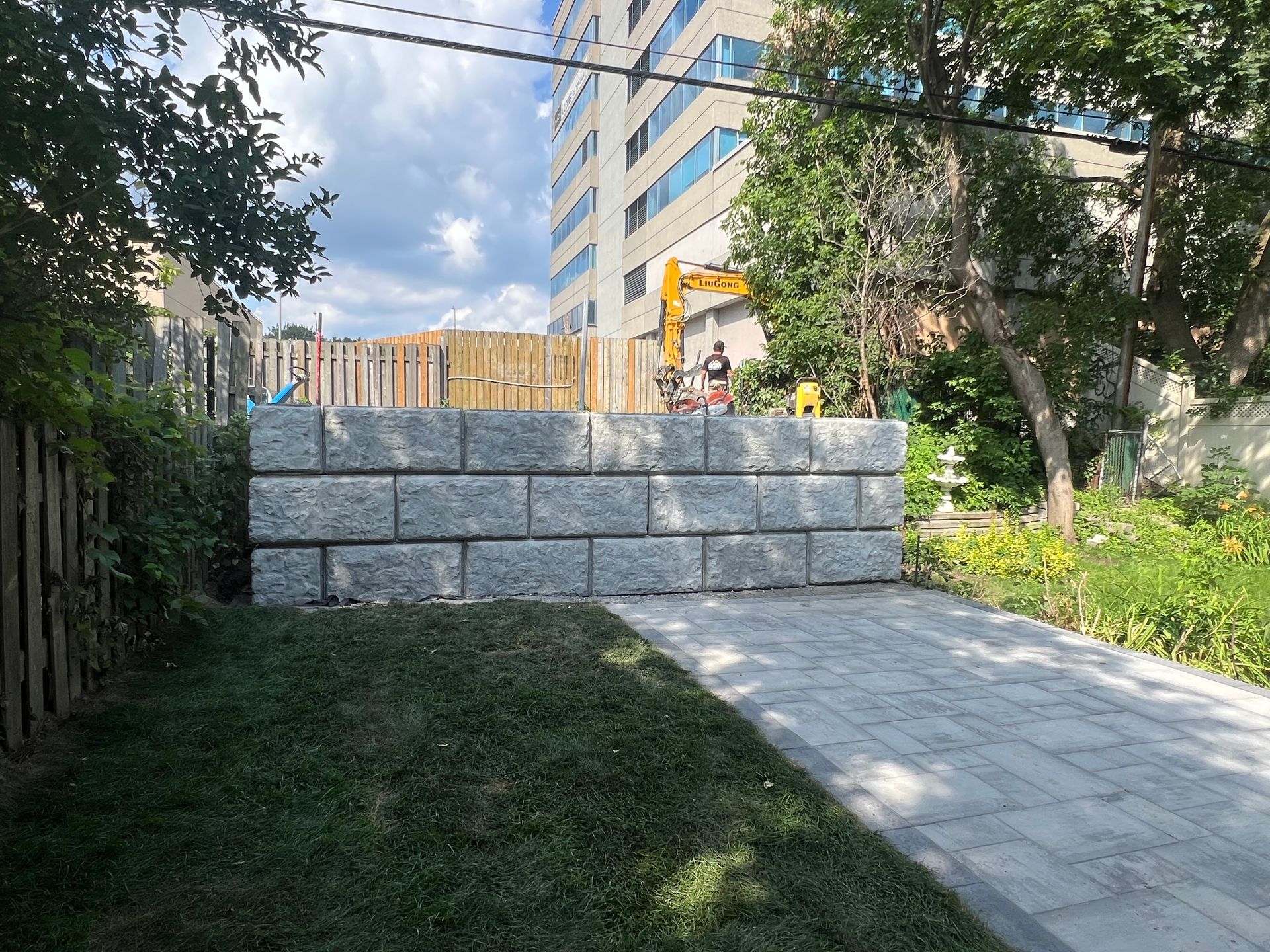 Un grand mur de pierre est en train d'être construit dans l'arrière-cour d'une maison.