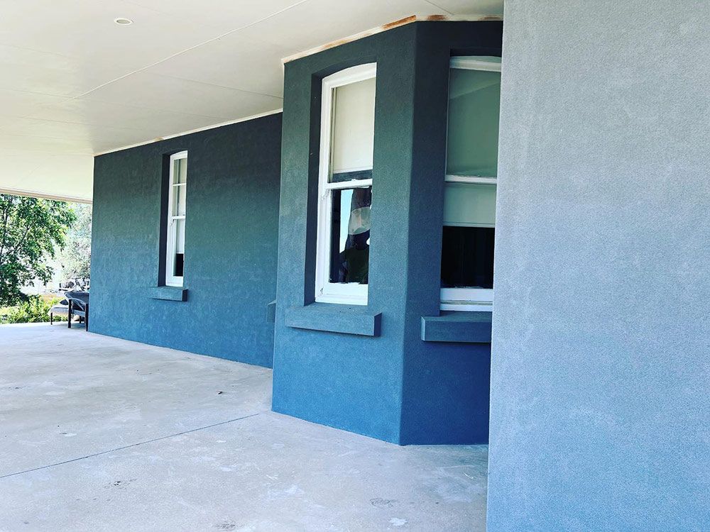 A Blue House With White Windows and a Concrete Porch — S & S Tiling and Rendering in Forbes, NSW