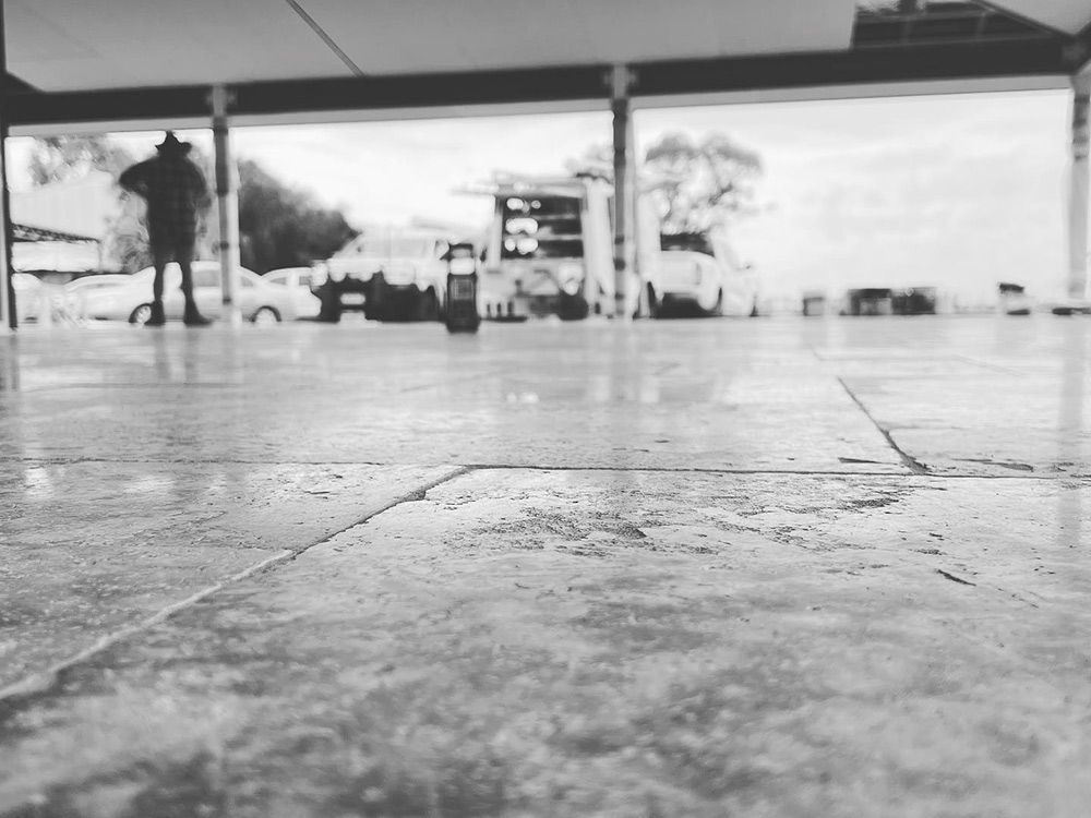 Black and White Photo of Concrete Floor With Person in Background — S & S Tiling and Rendering in Dubbo, NSW