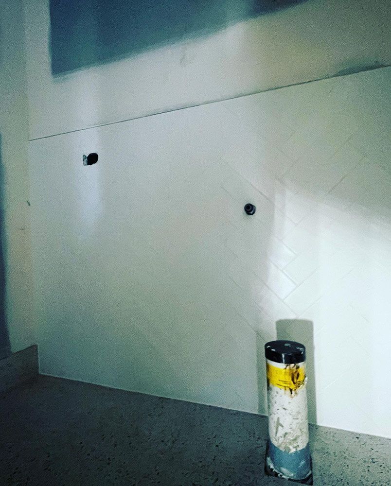 A White Wall With a Black Pipe in the Middle of It — S & S Tiling and Rendering in Dubbo, NSW