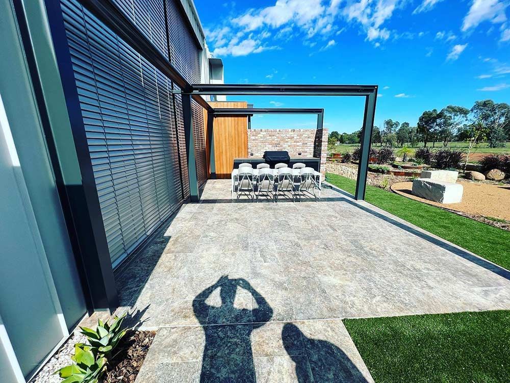 A Shadow of a Person is Cast on a Patio in Front of a House — S & S Tiling and Rendering in Orange, NSW