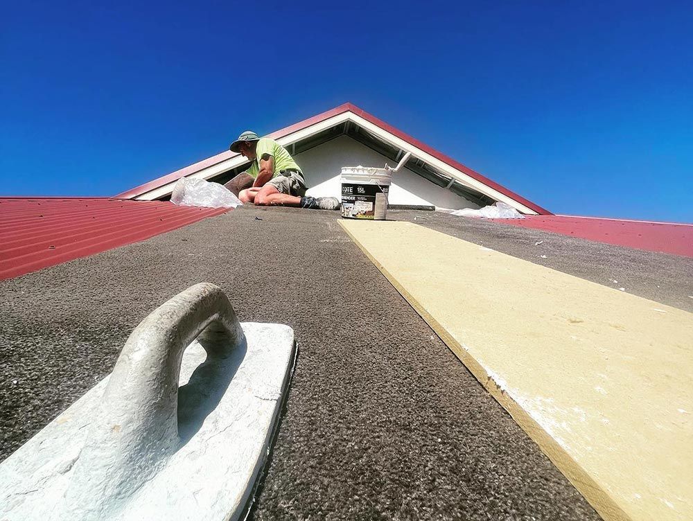A Man is Working on the Roof of a Building — S & S Tiling and Rendering in Bourke, NSW