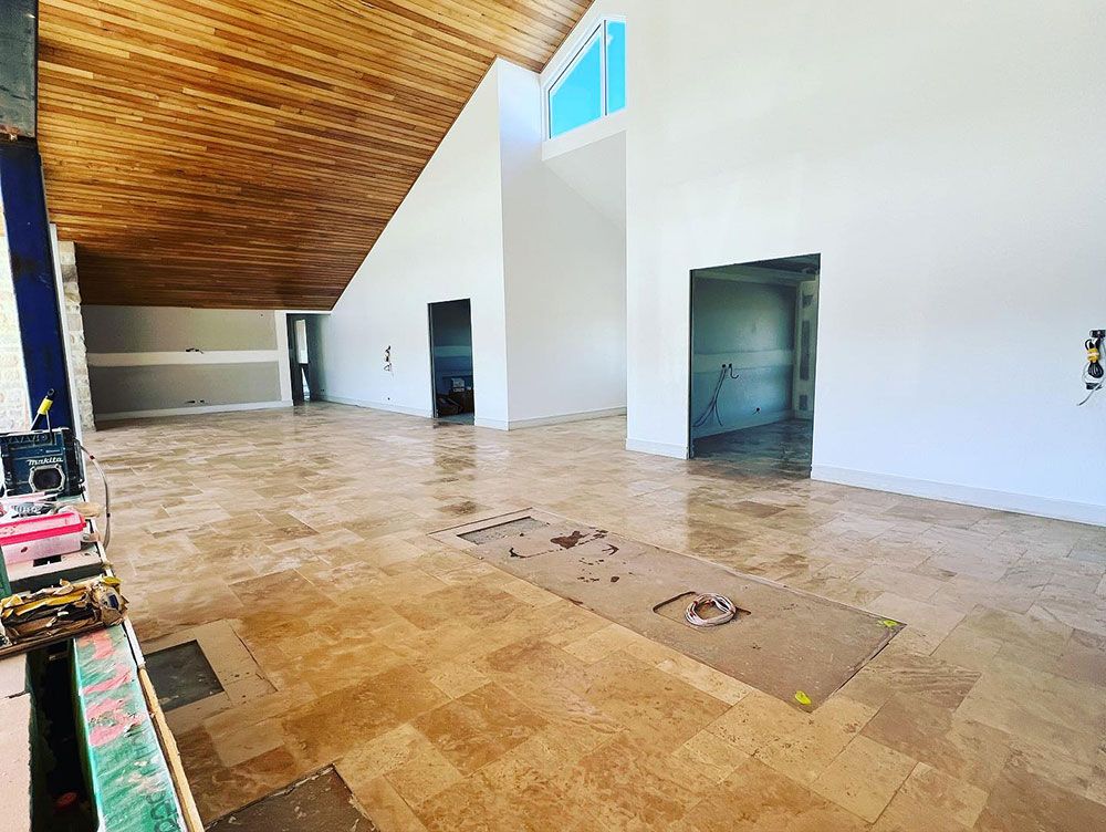 A Large Empty Room With a Tiled Floor and a Wooden Ceiling — S & S Tiling and Rendering in Orange, NSW