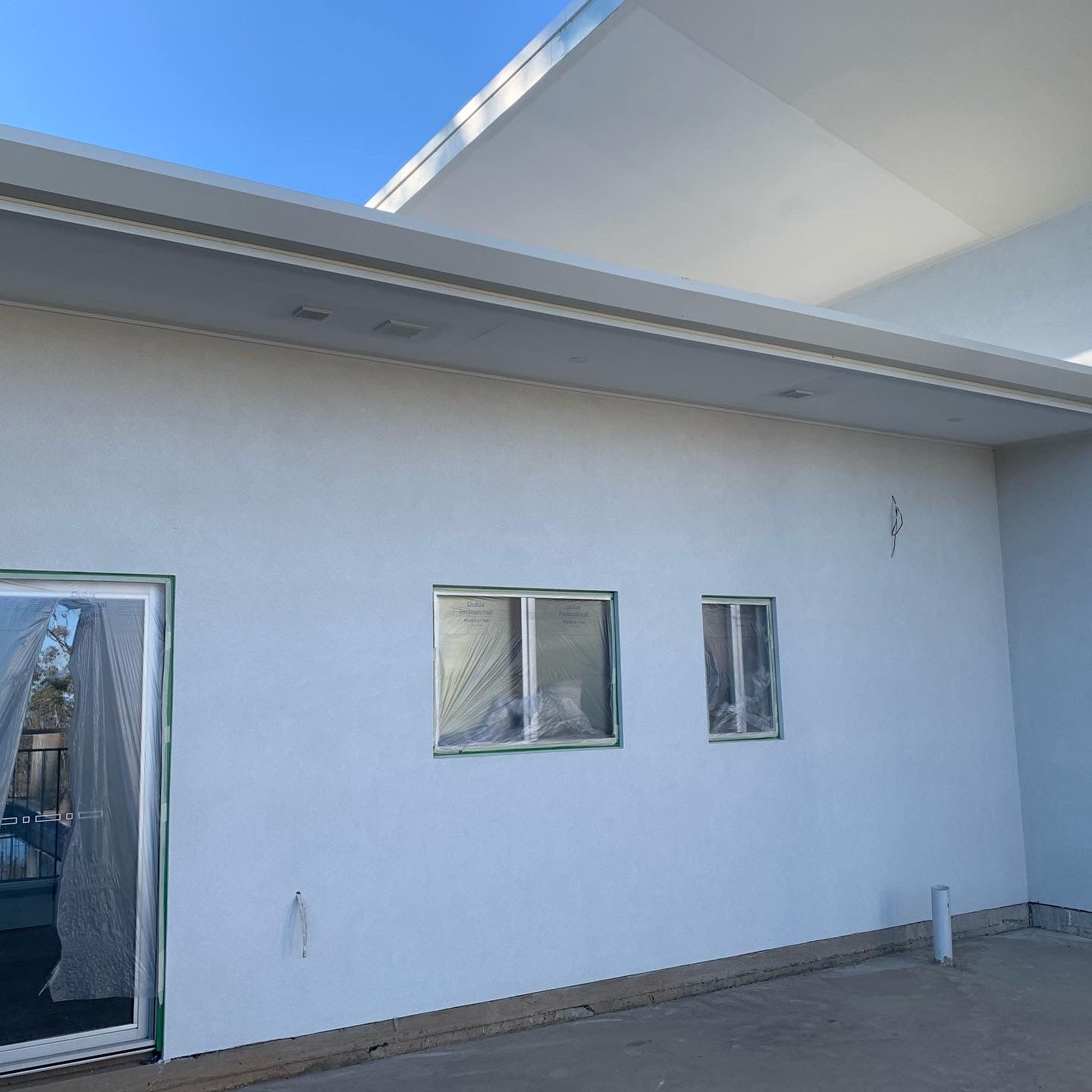 A White Building With Three Windows and a Sliding Glass Door — S & S Tiling and Rendering in Parkes, NSW