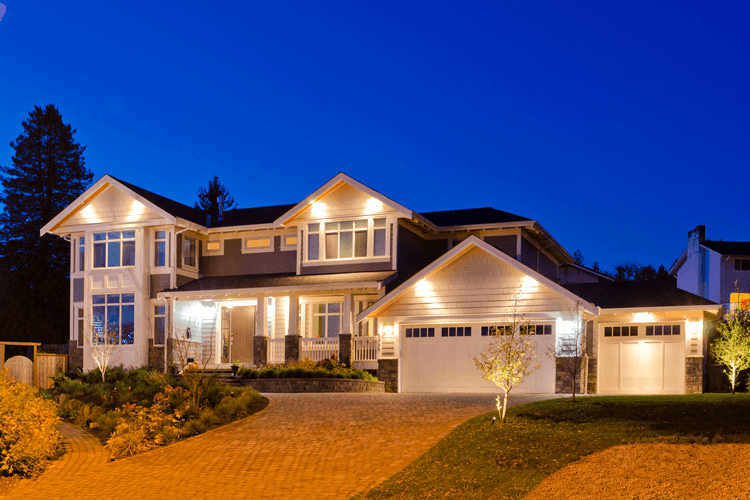 A large house is lit up at night in a residential area.