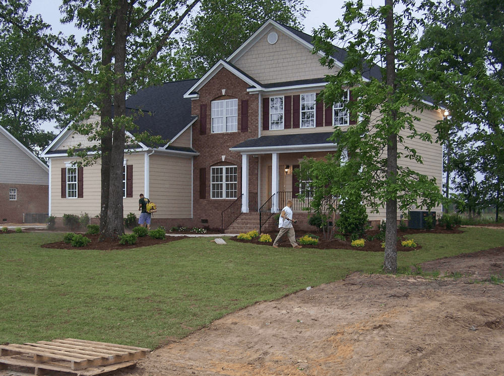 A man is walking in front of a large house