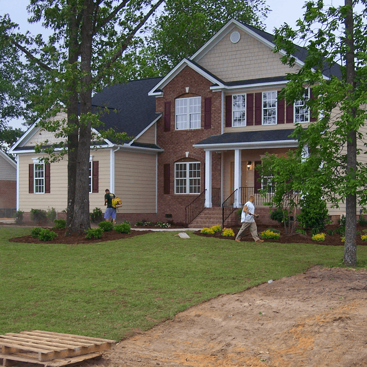 A man walking in front of a large house