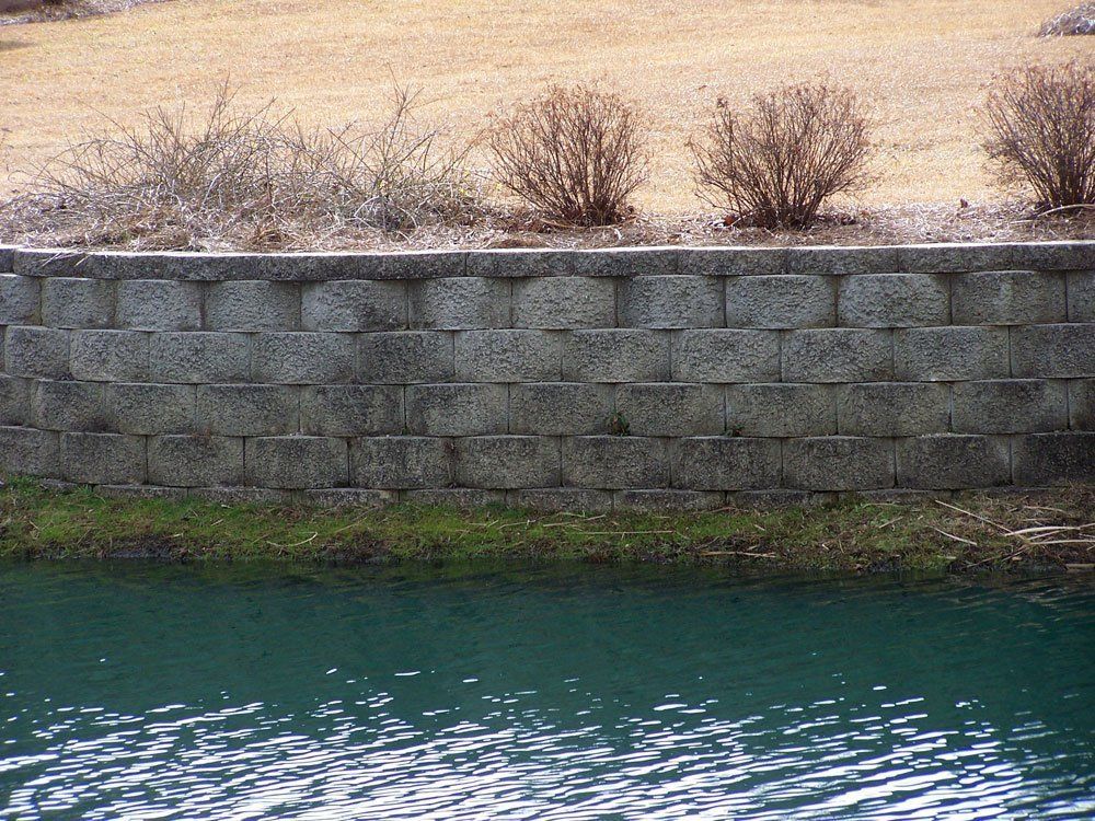 A stone wall surrounds a body of water.