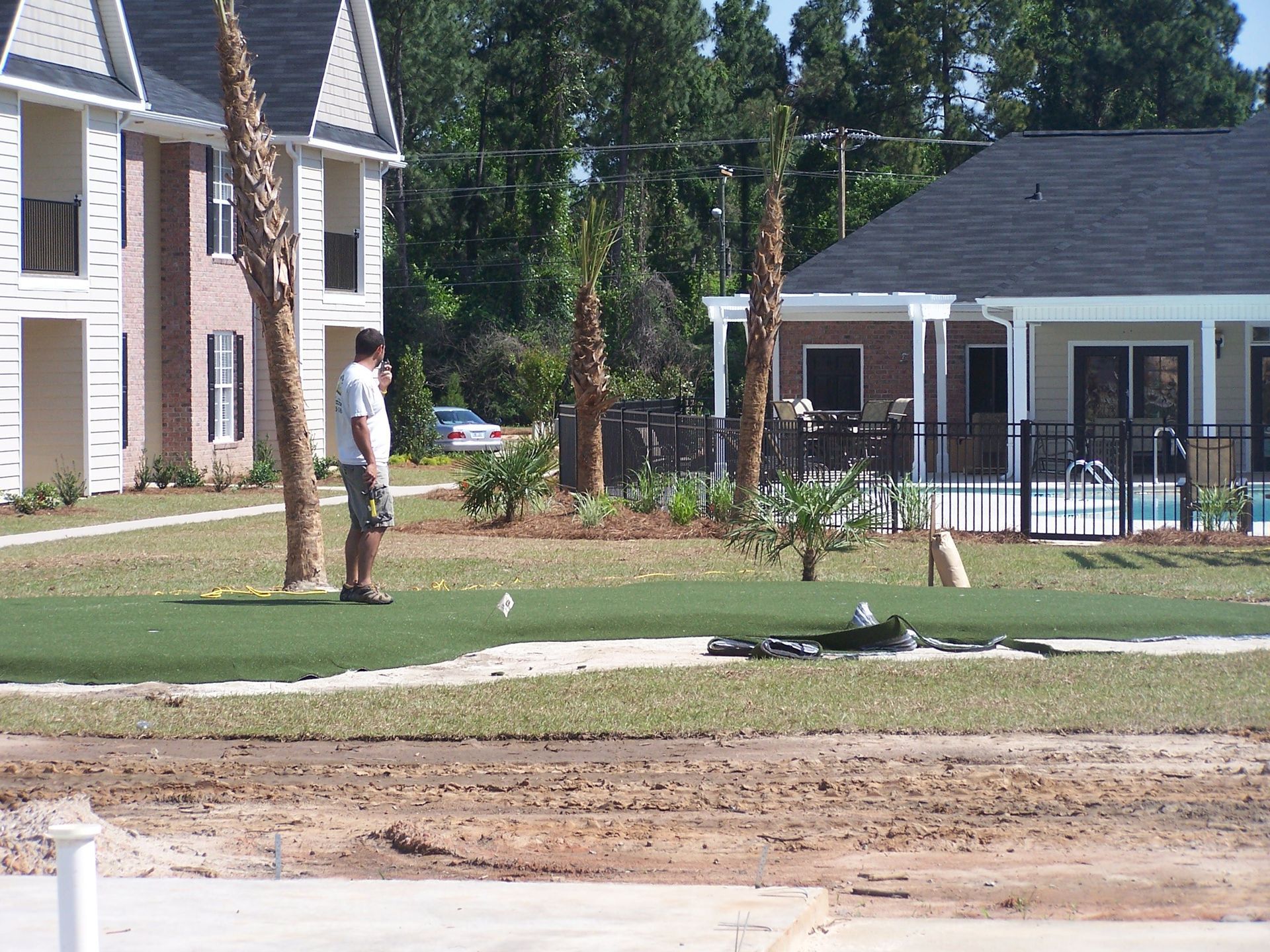 A man is standing on a golf course in front of a house