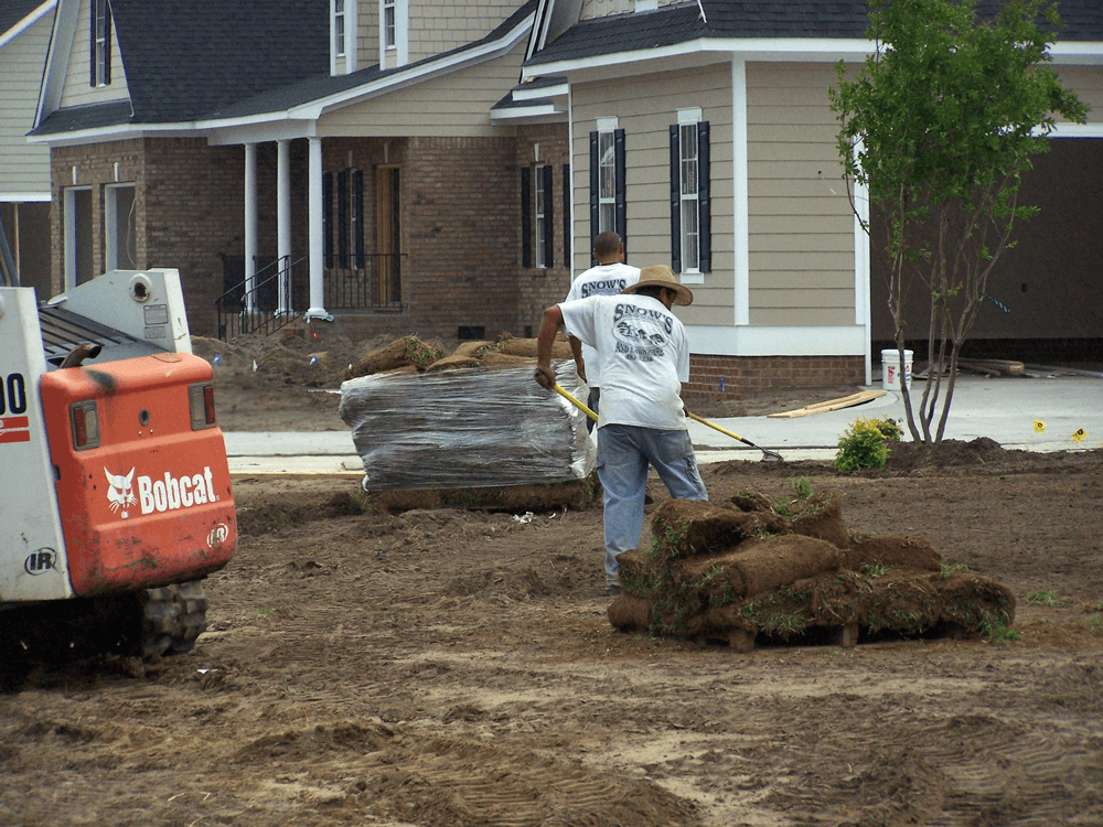 A bobcat tractor is parked in front of a house