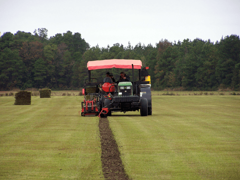A tractor with a red canopy is plowing a field