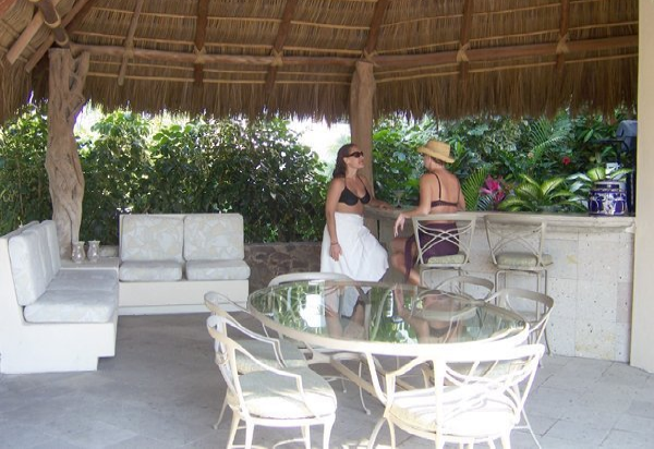Two women sitting at a table under a thatched roof