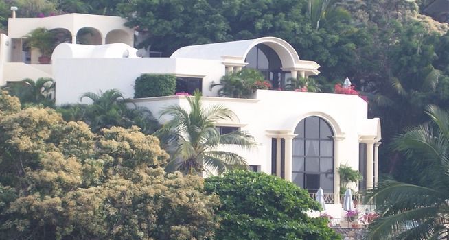 a large white villa surrounded by trees and palm trees