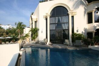 back of a large white villa with a swimming pool