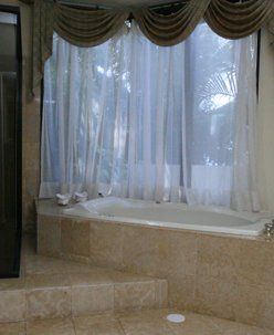 A bathroom with a tub and a window with curtains.