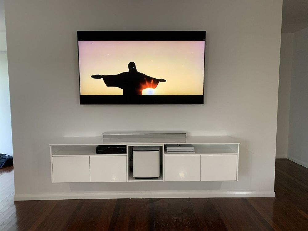 A Flat Screen Tv Is Mounted on A Wall Above a White Entertainment Center — T.N. Locke Communications In Kirwan, QLD