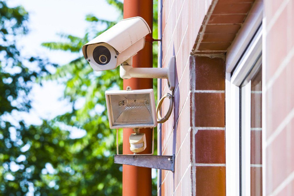 A Security Camera Is Mounted on The Side of A Building Next to A Window — T.N. Locke Communications In Kirwan, QLD