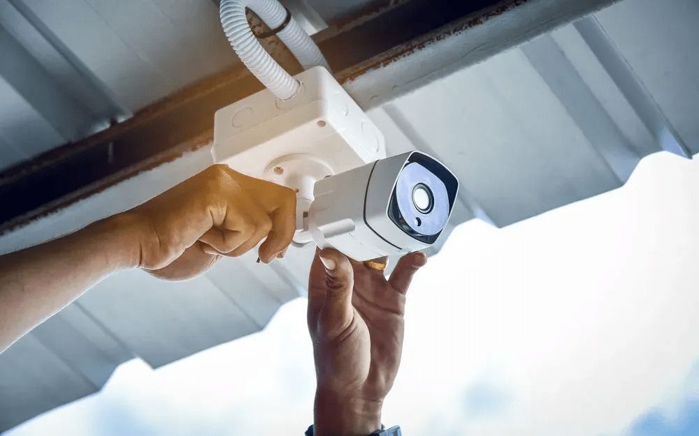 A Person Is Installing a Security Camera on The Roof of A Building — T.N. Locke Communications In Kirwan, QLD