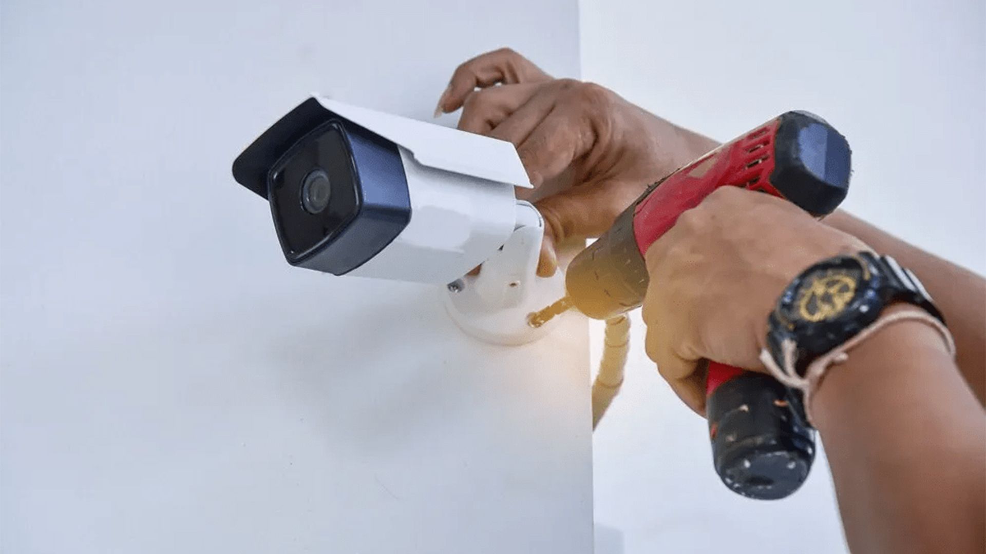 A Person is Installing a Security Camera on a Wall With a Drill — T.N. Locke Communications In Charters Towers, QLD