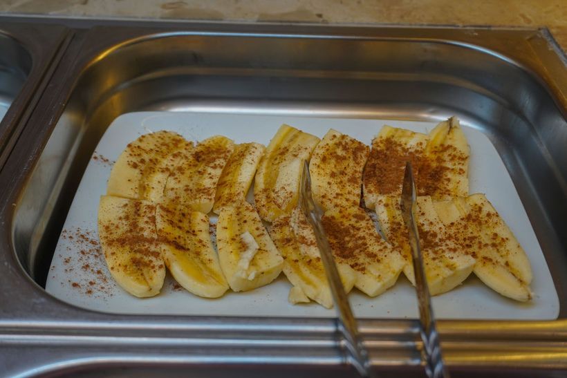 Uma bandeja de bananas fatiadas com canela e pinça.