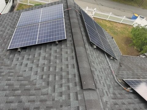 Roof with solar panels on gray shingles, viewed from above