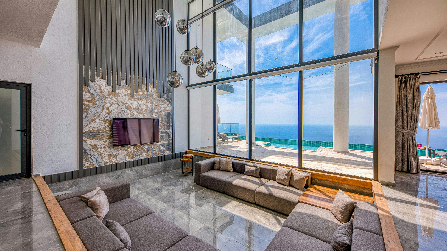 Modern seaside living room with floor-to-ceiling windows, ocean view, gray sofas, and a sleek fireplace