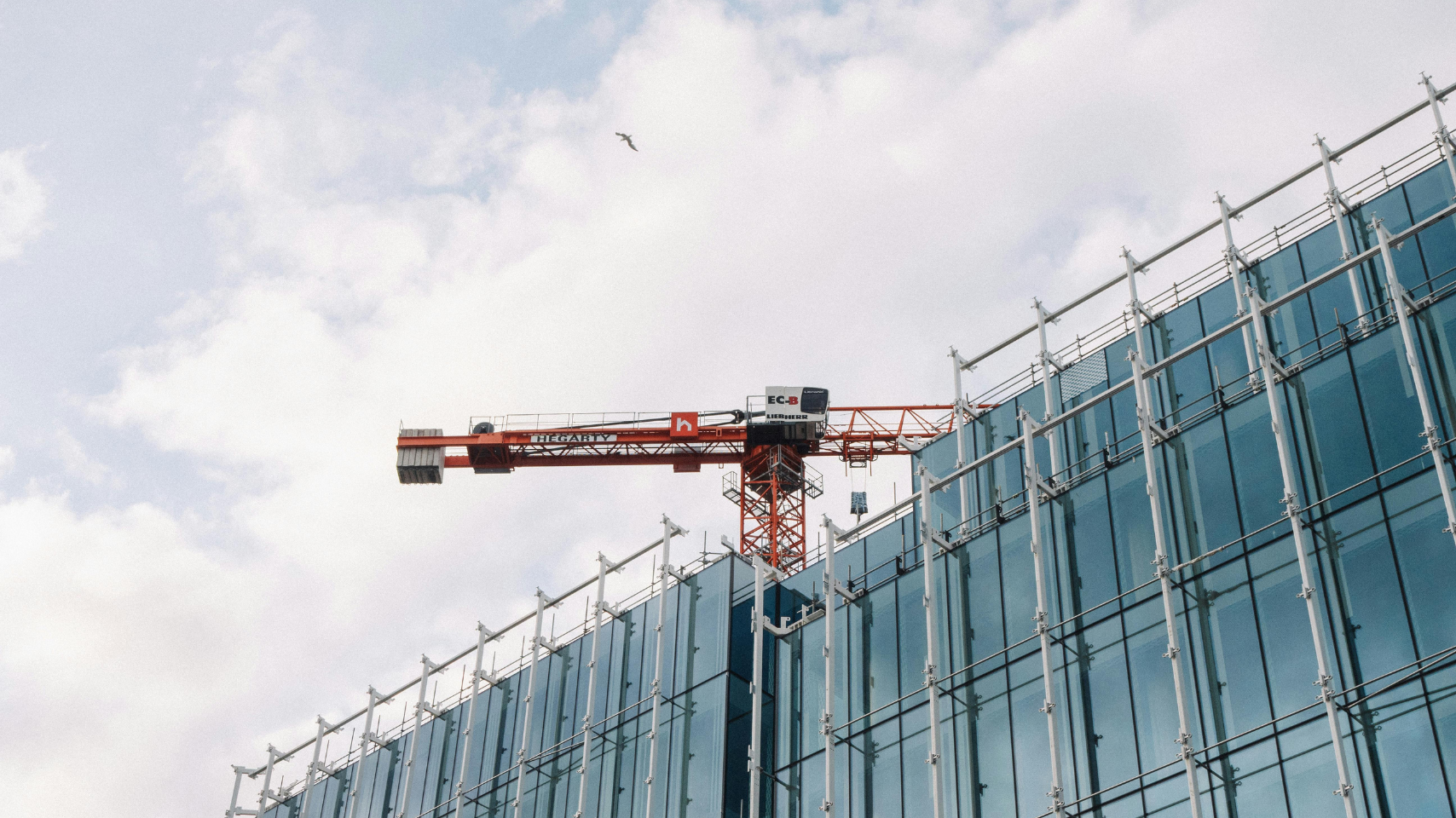 Construction crane above a modern glass building under renovation