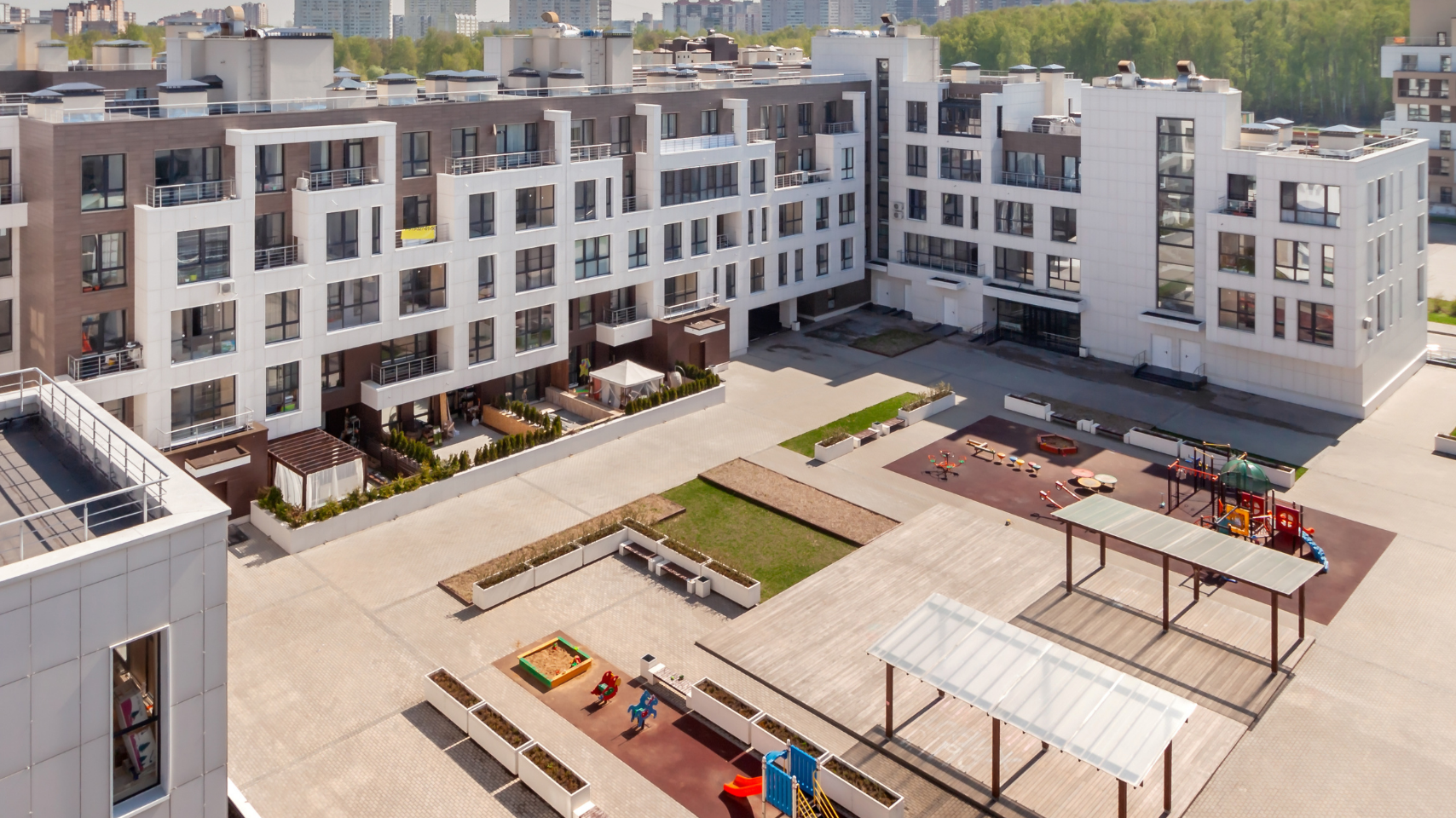 Modern apartment complex courtyard with benches, patio seating, and a rooftop view