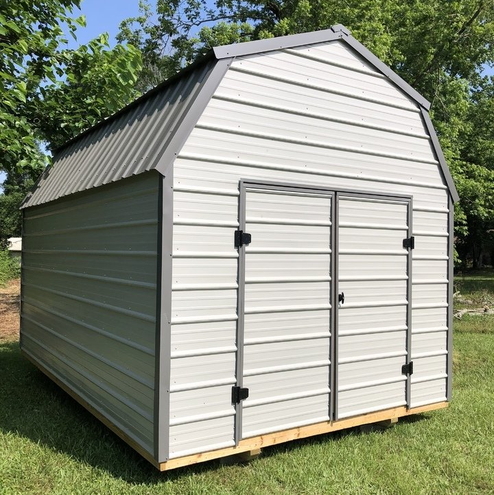 Superior Outdoor Centers metal lofted barn A white metal shed is sitting in the middle of a grassy field.