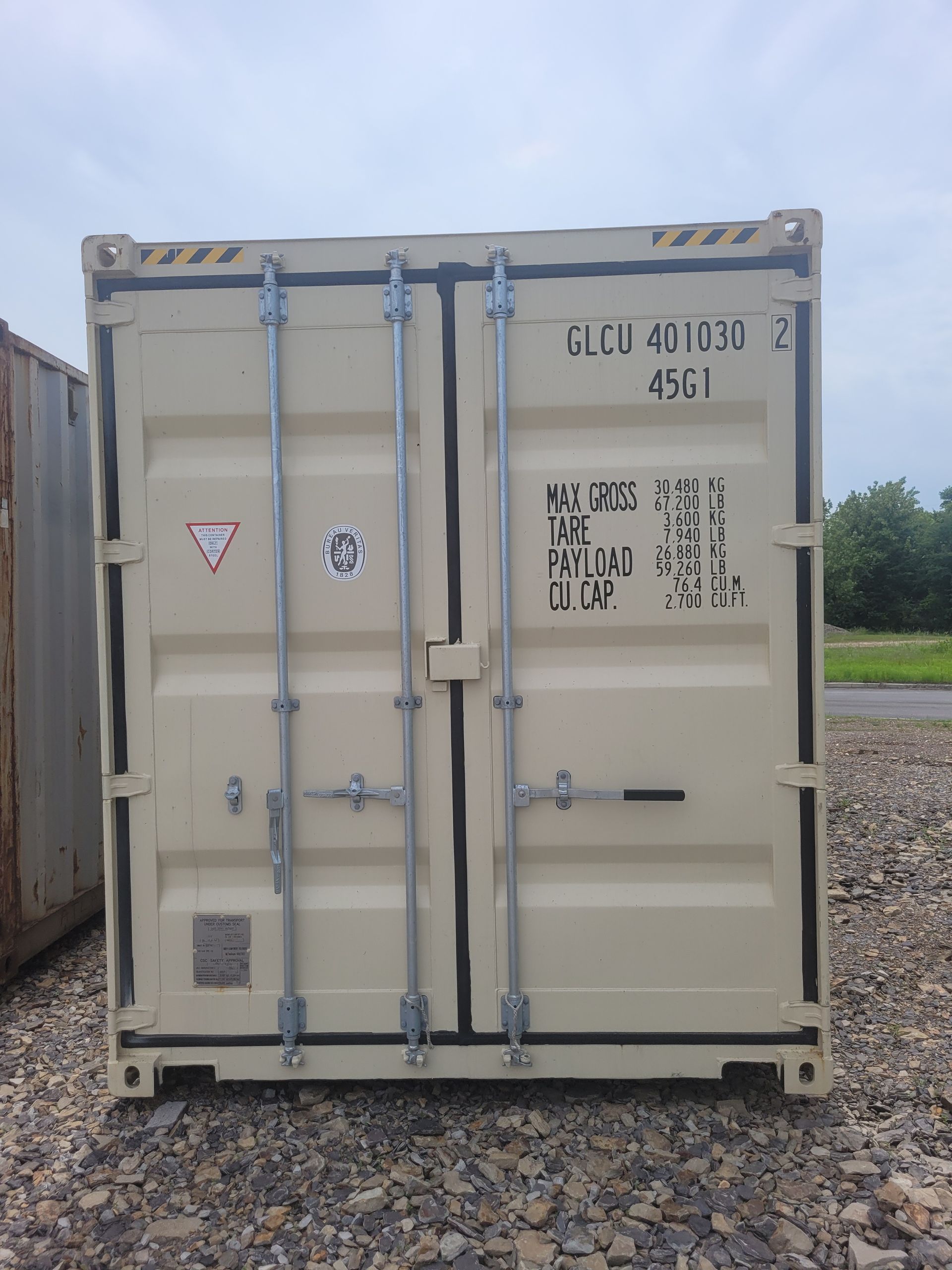 A shipping container is sitting on top of a gravel lot.