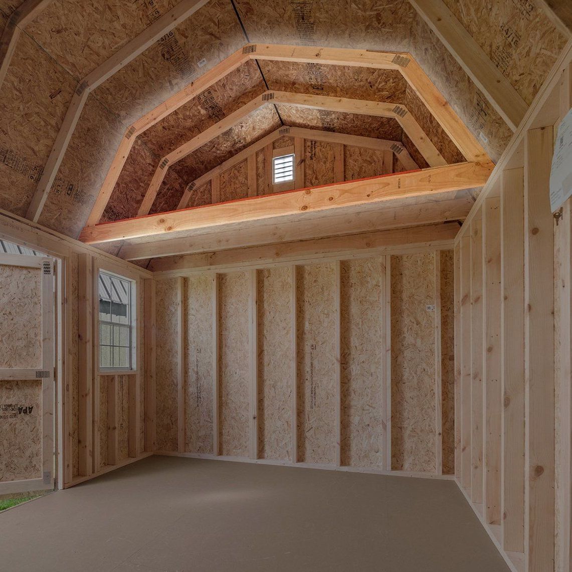 The inside of a wooden shed with a vaulted ceiling and a window.