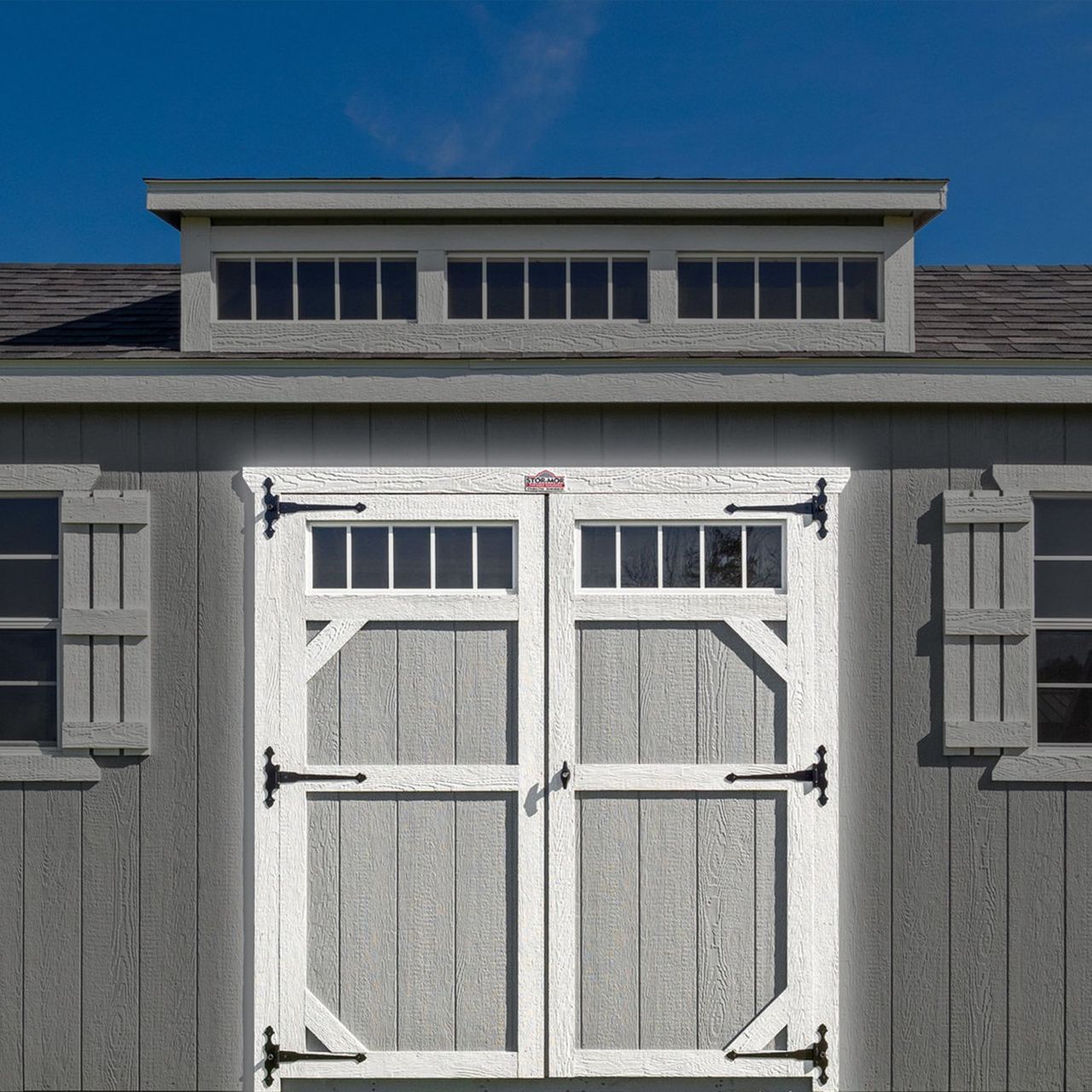 A gray shed with a white door and shutters