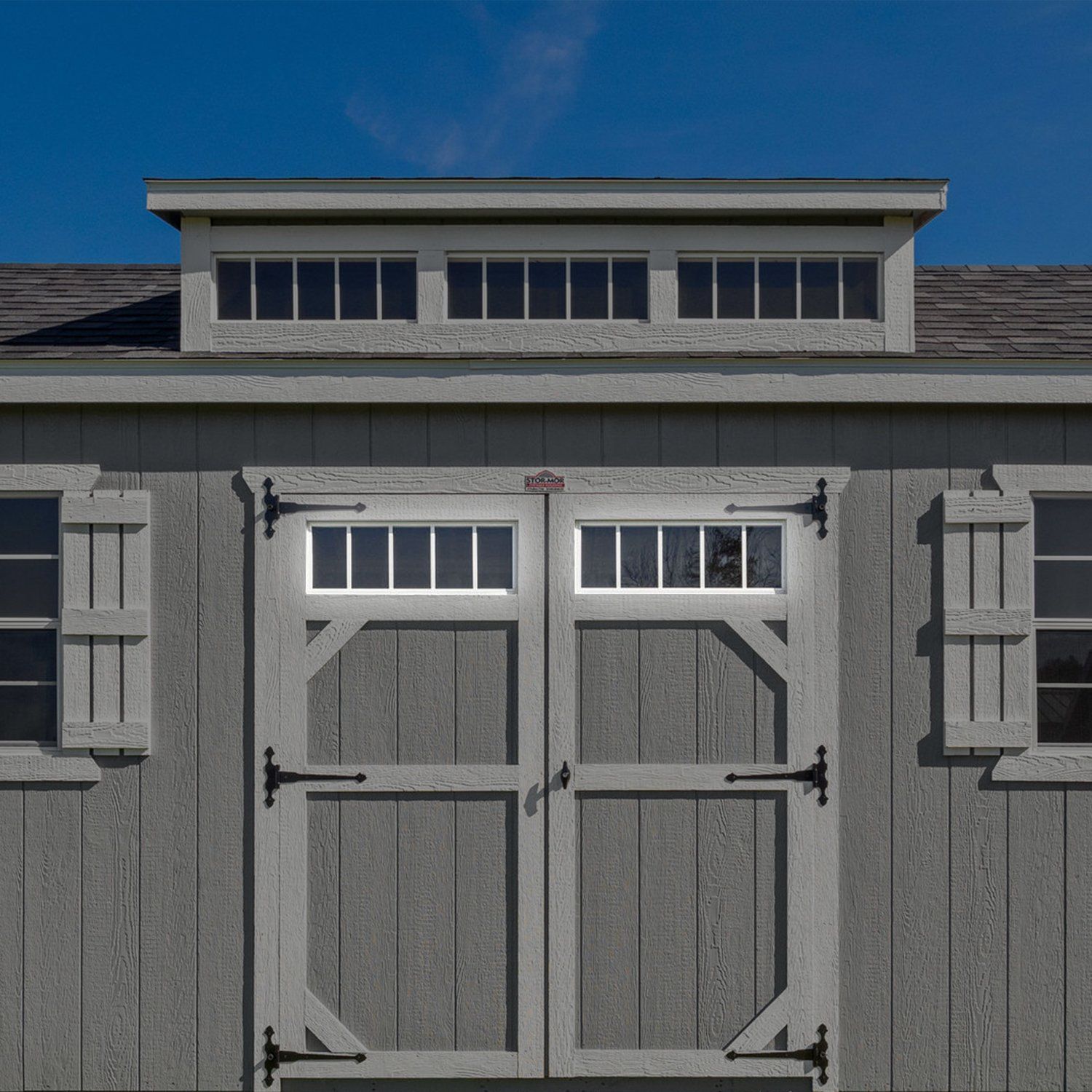 A shed with a roof that has a window above the door