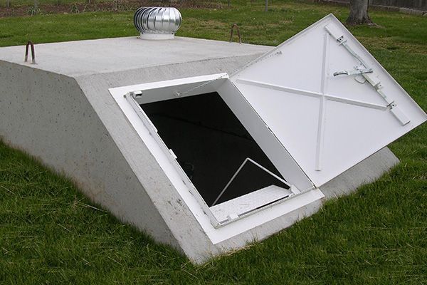 A concrete bunker with the door open and a fan on top of it