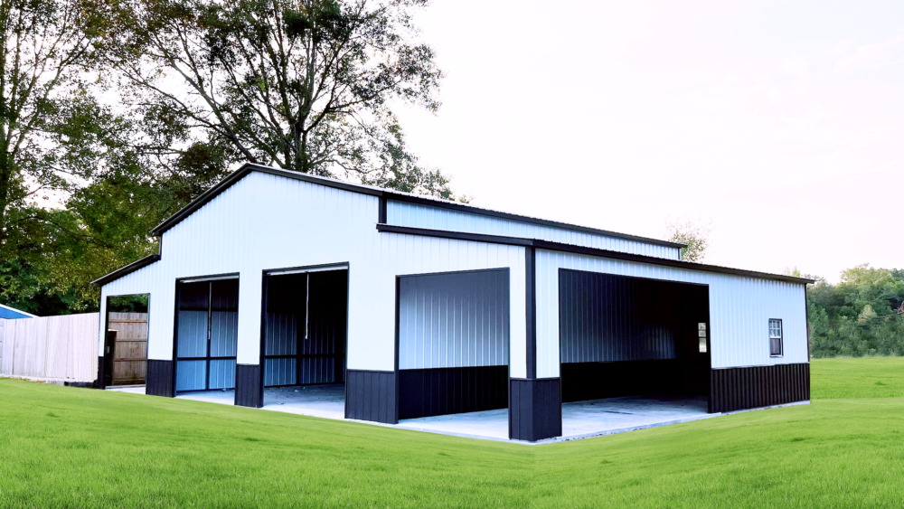 A white and black garage is sitting in the middle of a lush green field.