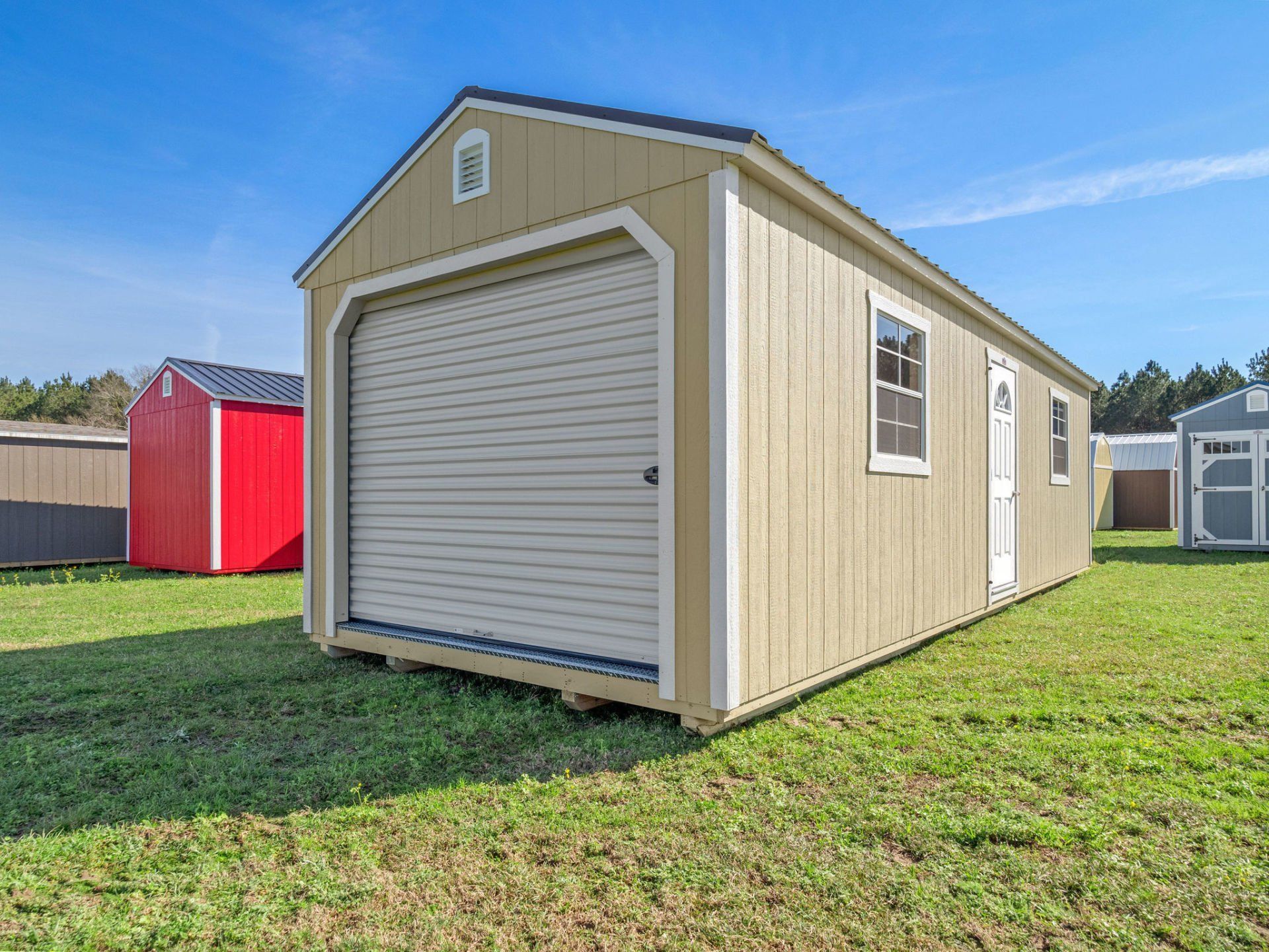 Superior Outdoor Centers  garage shed A small shed with a garage door is sitting in the middle of a grassy field.
