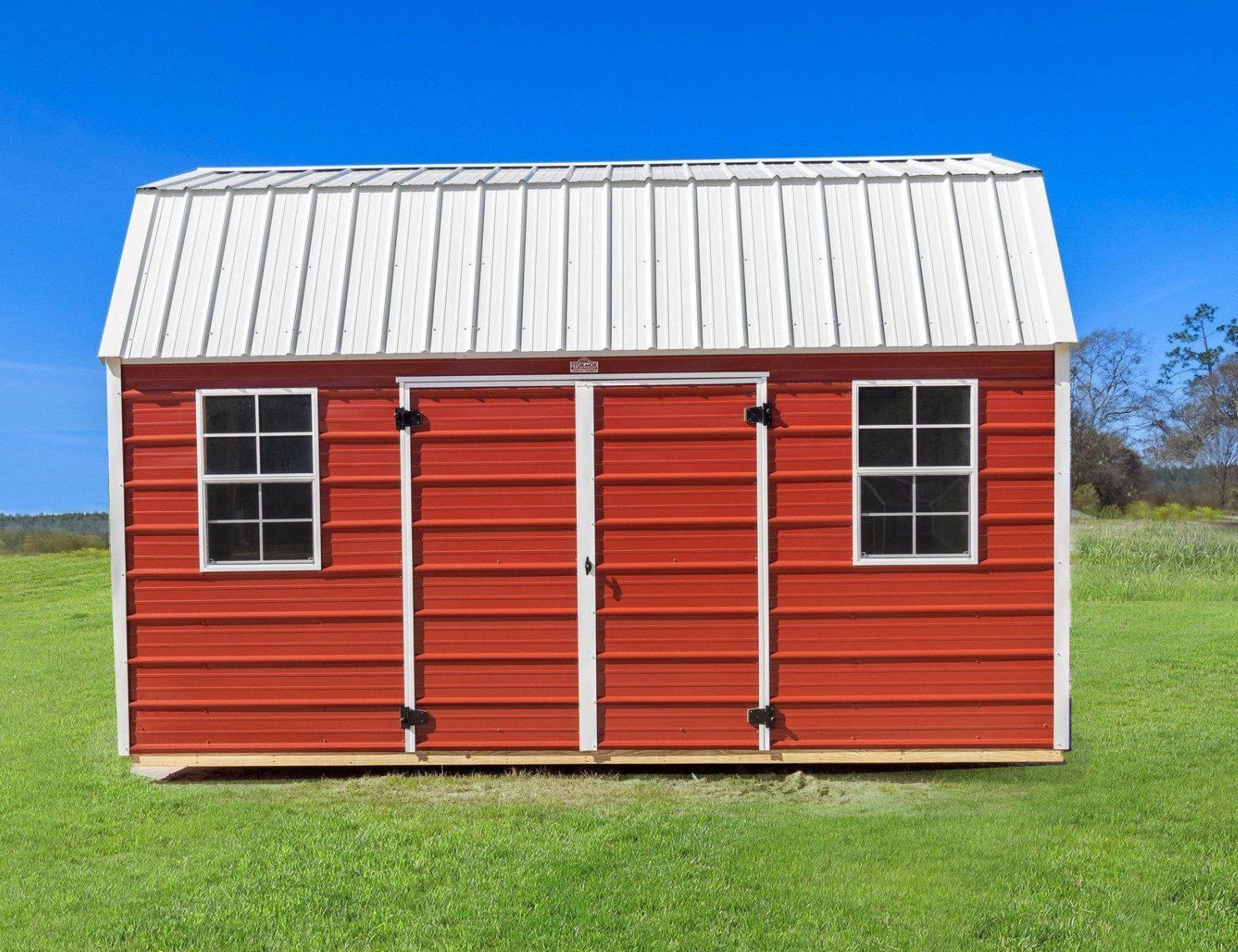 Superior Outdoor Centers metal side lofted barn A red barn with a white roof is sitting in the middle of a grassy field.